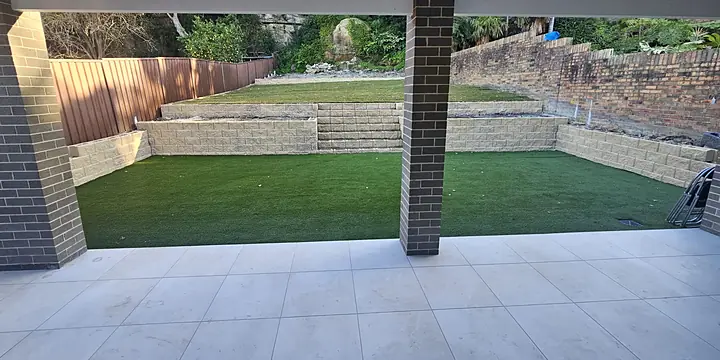 After: terraced block retaining walls, synthetic turf and a tiled alfresco