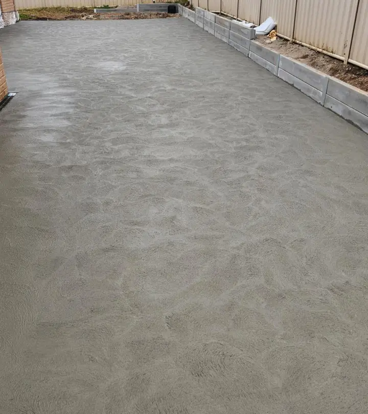 Freshly finished concrete slab running the length of a backyard